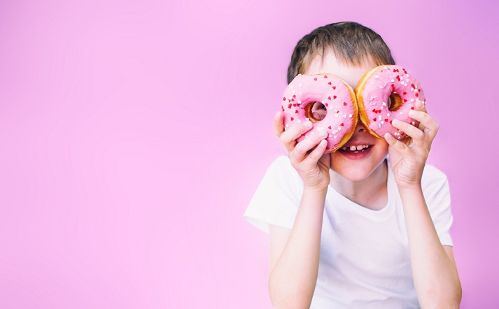 boy holding donuts to eyes