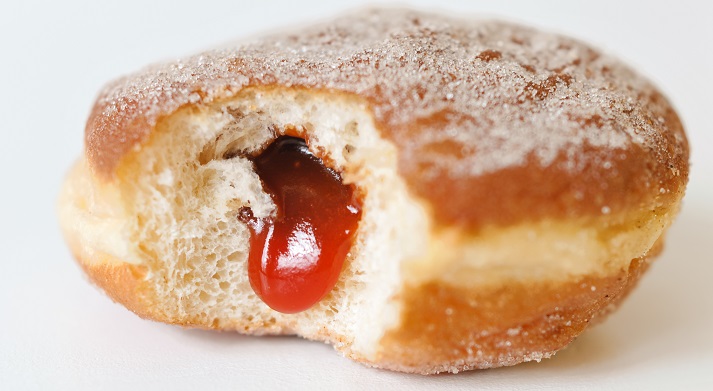 German fried donut, called Krapfen, Berliner or Pfannkuchen, filled with rose hip jam and dusted with cinnamon sugar, traditionally eaten at carnival and New Year's Eve