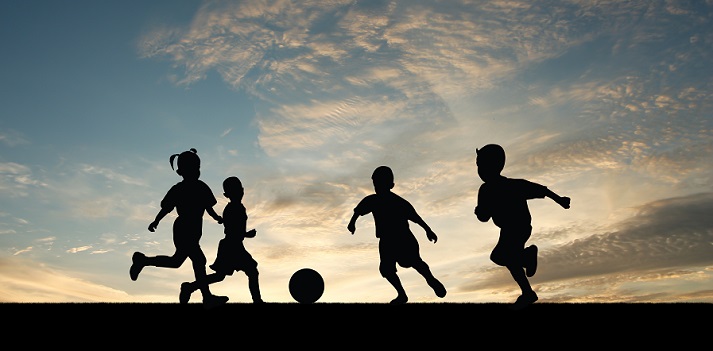 friends playing soccer at sunset