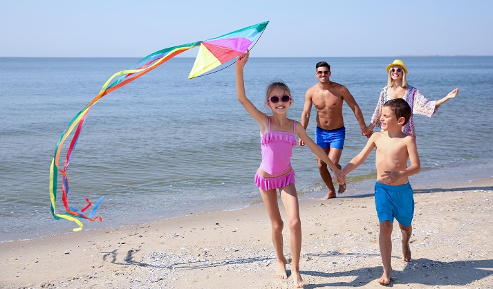 family flying kite on beach