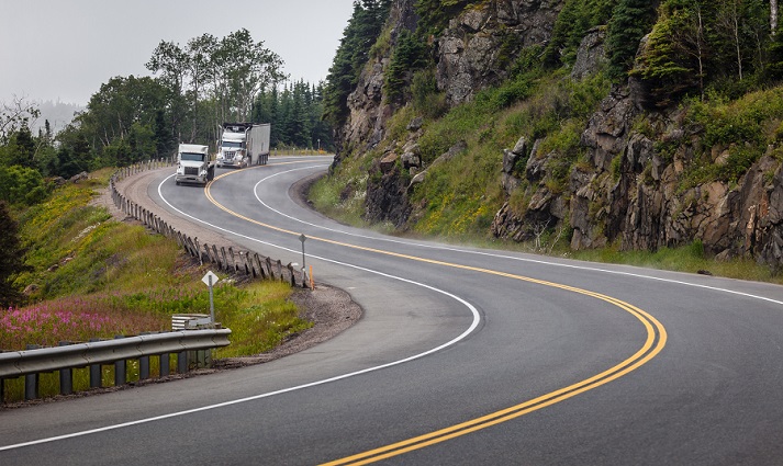 trucks driving down a steep, curved road