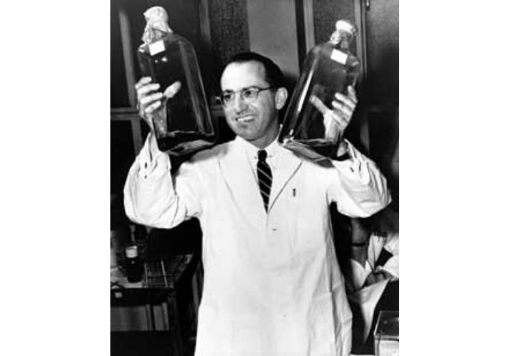 Salk with two bottles of culture used to grow polio vaccines, 1955
