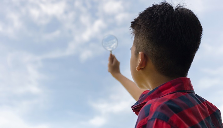boy studying the sky with a magnifying glass
