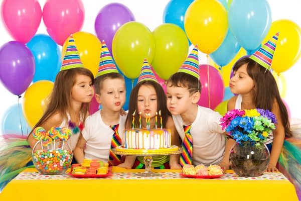 Kids celebrating birthday party and blowing candles on cake Kids celebrating birthday party